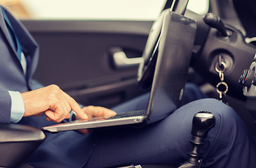 Image showing close up of young man with laptop driving car