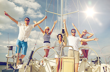 Image showing smiling friends sitting on yacht deck and greeting