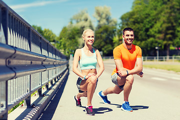 Image showing smiling couple stretching leg outdoors