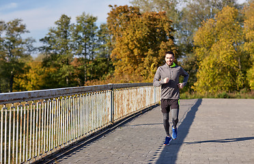 Image showing happy young man running over city bridge