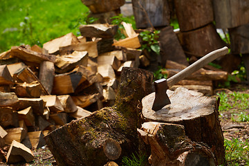 Image showing Old ax on log and firewood in the background