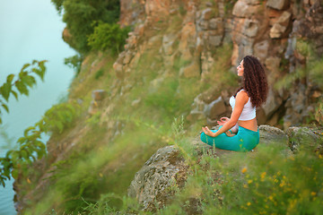 Image showing Young woman is practicing yoga near river