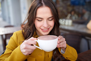 Image showing happy woman drinking cocoa at city street cafe