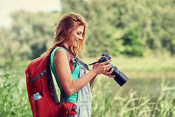 Image showing happy woman with backpack and camera outdoors