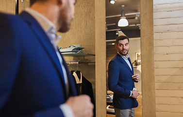 Image showing man trying jacket on at mirror in clothing store