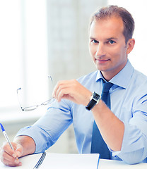 Image showing businessman with spectacles writing in notebook