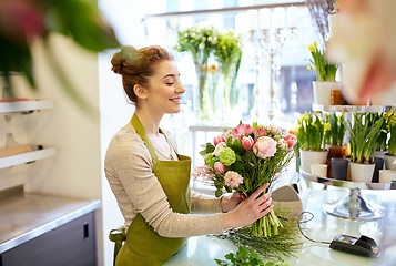 Image showing smiling florist woman making bunch at flower shop