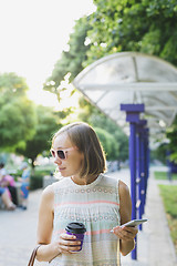 Image showing the woman with the phone drinking coffee in the Park