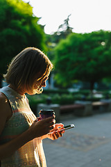 Image showing woman drinking coffee and looking at phone