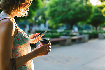 Image showing woman drinking coffee and looking at phone