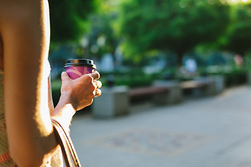Image showing woman walks down the street and drinks coffee