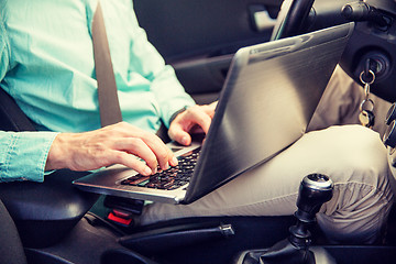 Image showing close up of young man with laptop driving car