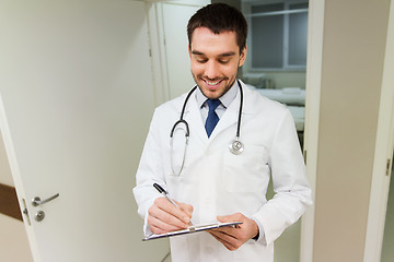 Image showing happy doctor writing to clipboard at hospital
