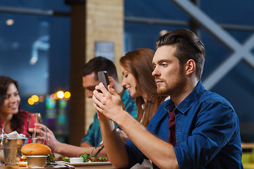 Image showing man with smartphone and friends at restaurant