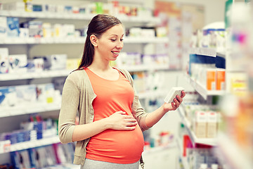 Image showing happy pregnant woman with medication at pharmacy