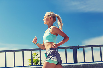 Image showing smiling young woman running outdoors