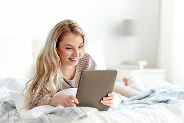 Image showing happy young woman with tablet pc in bed at home