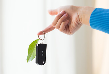 Image showing close up of hand holding car key with green leaf