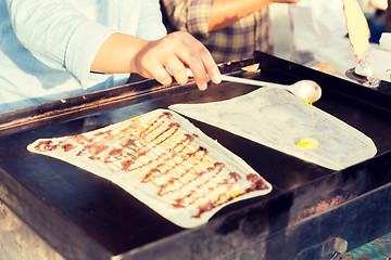 Image showing close up of cook frying pancakes at street market