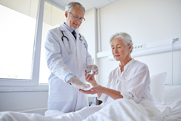 Image showing doctor giving medicine to senior woman at hospital