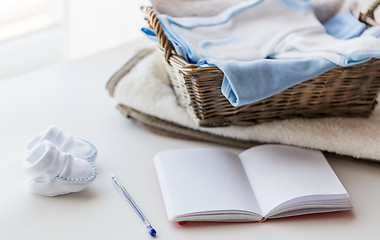 Image showing close up of baby clothes for newborn and notebook