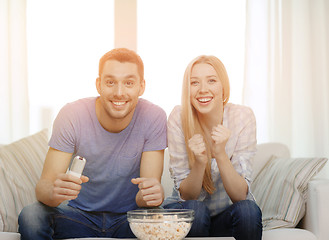 Image showing smiling couple with popcorn cheering sports team