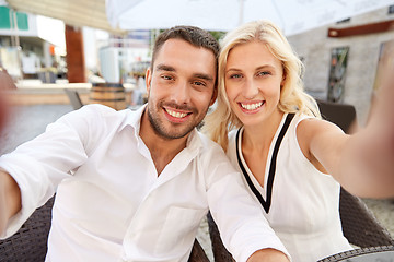 Image showing happy couple taking selfie at restaurant terrace