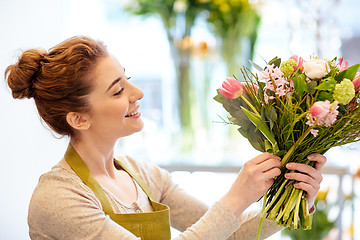 Image showing smiling florist woman making bunch at flower shop