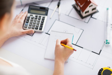 Image showing close up of hand on blueprint writing to notebook