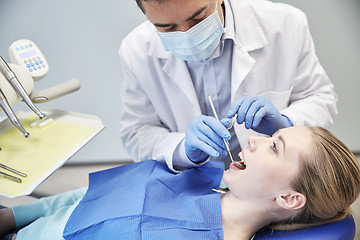Image showing male dentist in mask checking female patient teeth