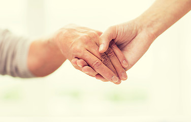 Image showing close up of senior and young woman holding hands