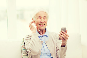 Image showing senior woman with smartphone and earphones at home