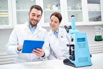Image showing scientists with tablet pc and microscope in lab