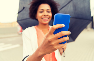 Image showing close up of woman with umbrella and smartphone