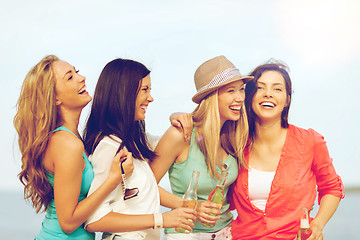 Image showing smiling girls with drinks on the beach