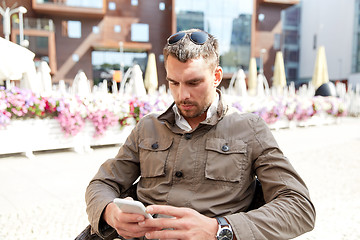 Image showing young man texting on smartphone at city terrace