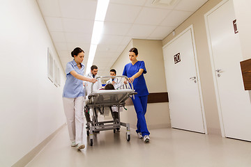 Image showing medics with woman on hospital gurney at emergency