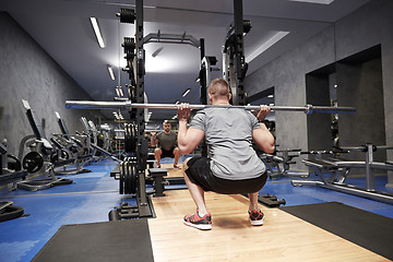 Image showing young man flexing muscles with bar in gym