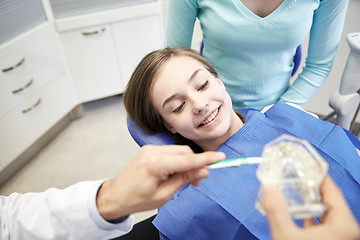 Image showing happy dentist showing toothbrush to patient girl