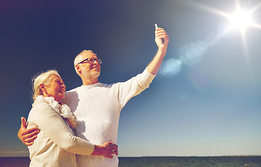 Image showing seniors with smartphone taking selfie on beach