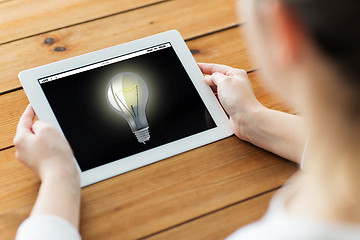 Image showing close up of woman with tablet pc on wooden table