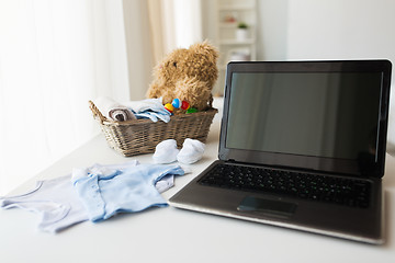 Image showing close up of baby clothes, toys and laptop at home