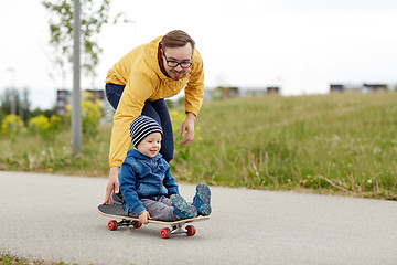 Image showing happy father and little son riding on skateboard