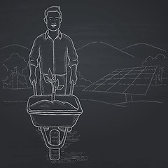 Image showing Man with plant and wheelbarrow.