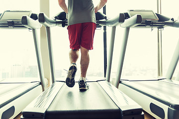 Image showing close up of male legs running on treadmill in gym