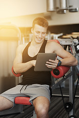 Image showing smiling young man with tablet pc computer in gym