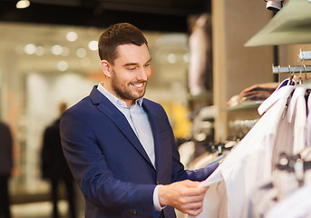 Image showing happy young man choosing clothes in clothing store
