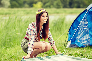 Image showing happy young woman laying blanket at campsite