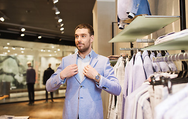 Image showing happy young man trying suit at clothing store