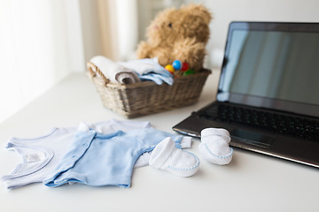 Image showing close up of baby clothes, toys and laptop at home